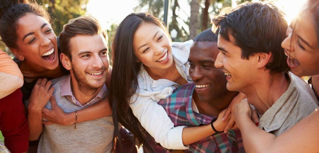 A group of friends in interracial couples, laughing and smiling with their partners