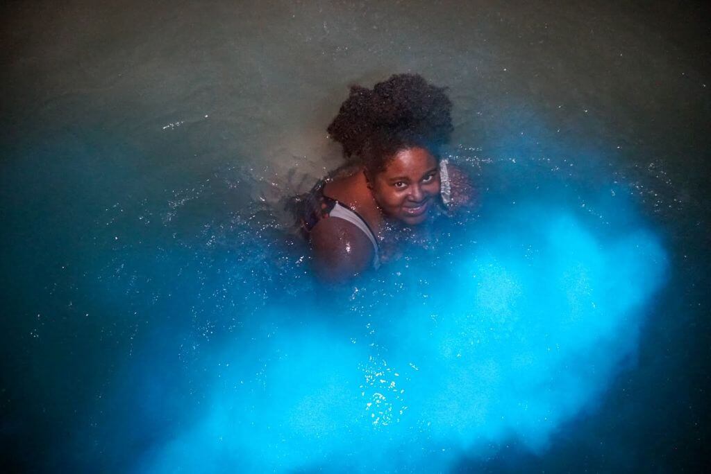 Black tourist swimming in neon blue waters at Luminous lagoon in Falmouth, Trelawny, Jamaica.  