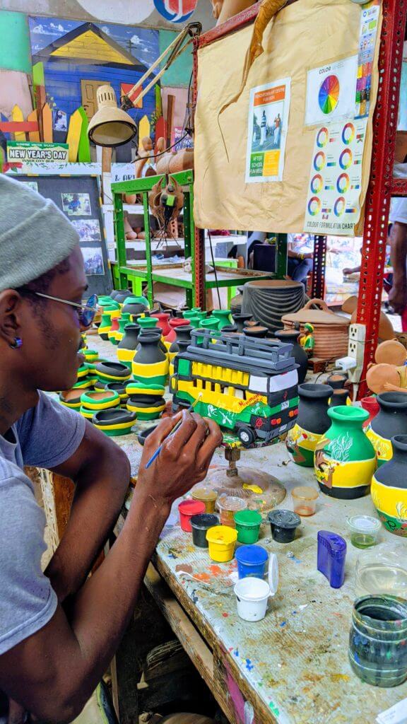 Black artist paints a ceramic bus in black green and gold