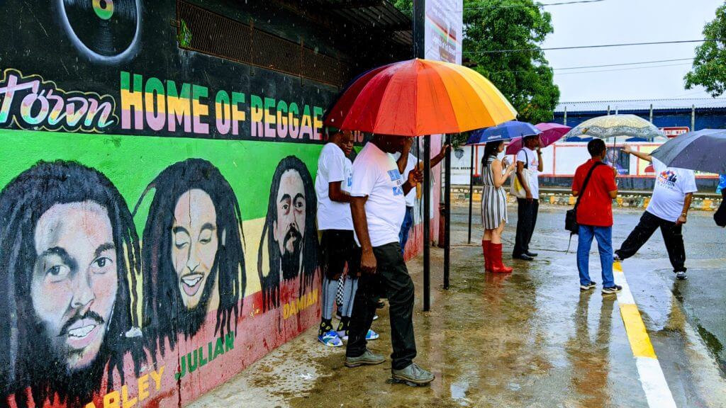 Group of people wait in the rain at trench Town in downtown jamaica