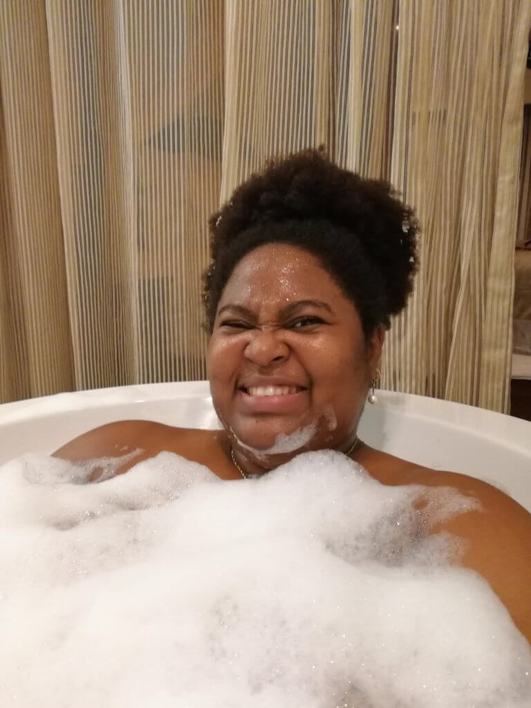 happy black woman relaxing in a bathtub of bubbles and soapy foam