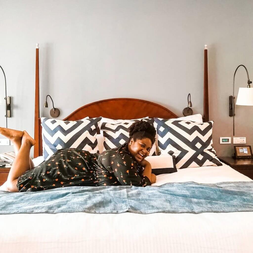 Black plus size woman relaxing in bed as a self-care routine that boosts productivity