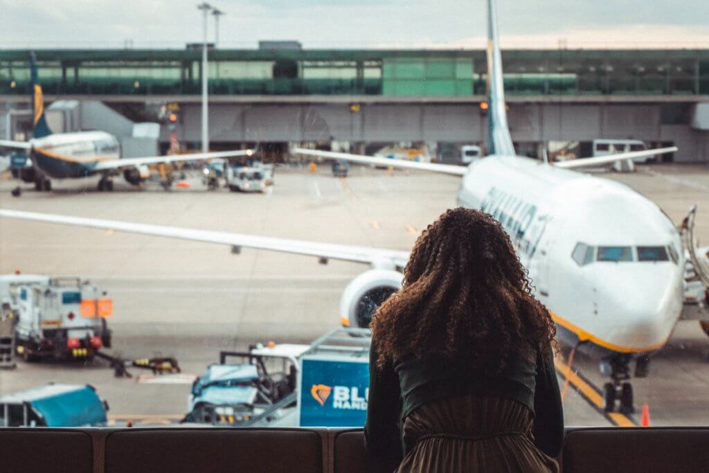 balck woman at airport terminal_airline rebooking and cancellation policies for Jamaicans stuck abroad due to COVID19