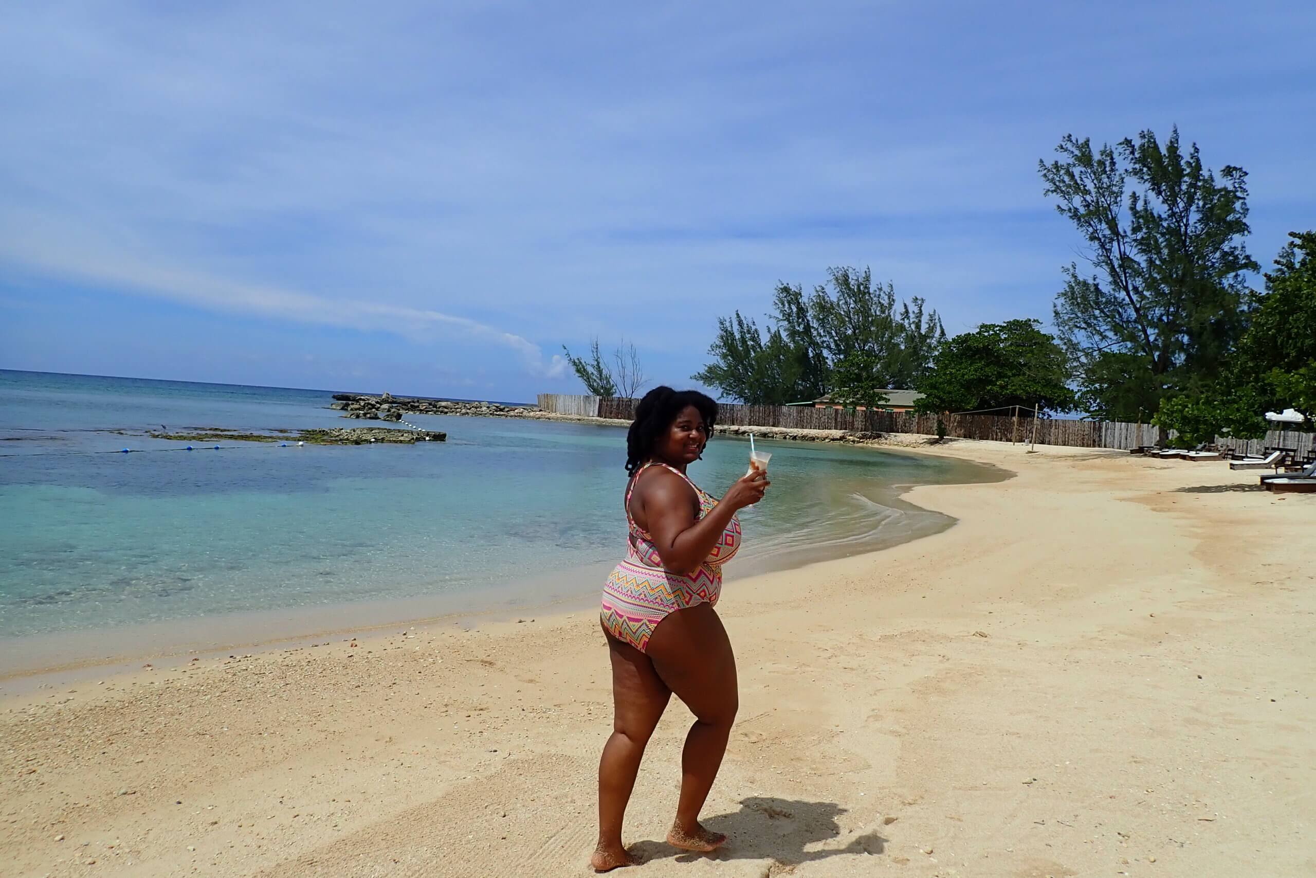 Why Carbbean Women Should solo travel more-black woman on a beach with a cocktail-diedreinwanderland