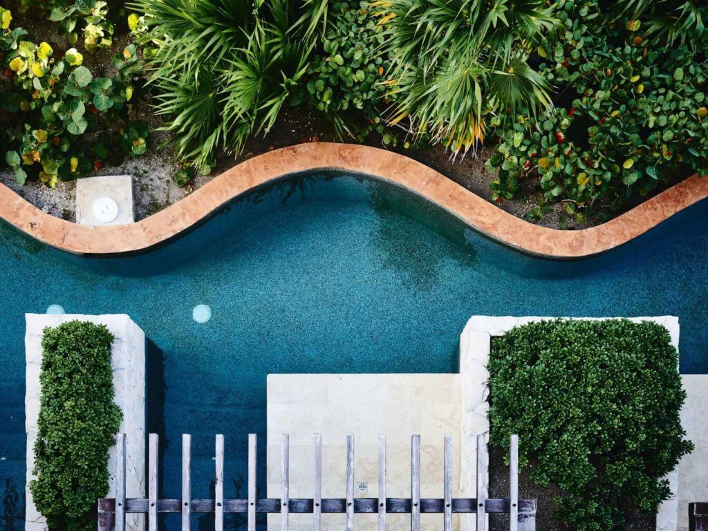 aerial drone shote of caribbean resort with curved stone path leading from the ppol